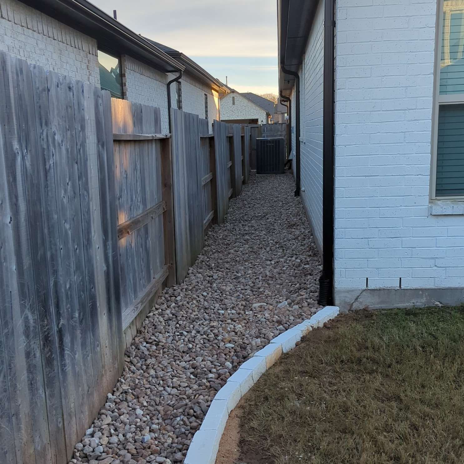 A narrow path between two houses with a wooden fence