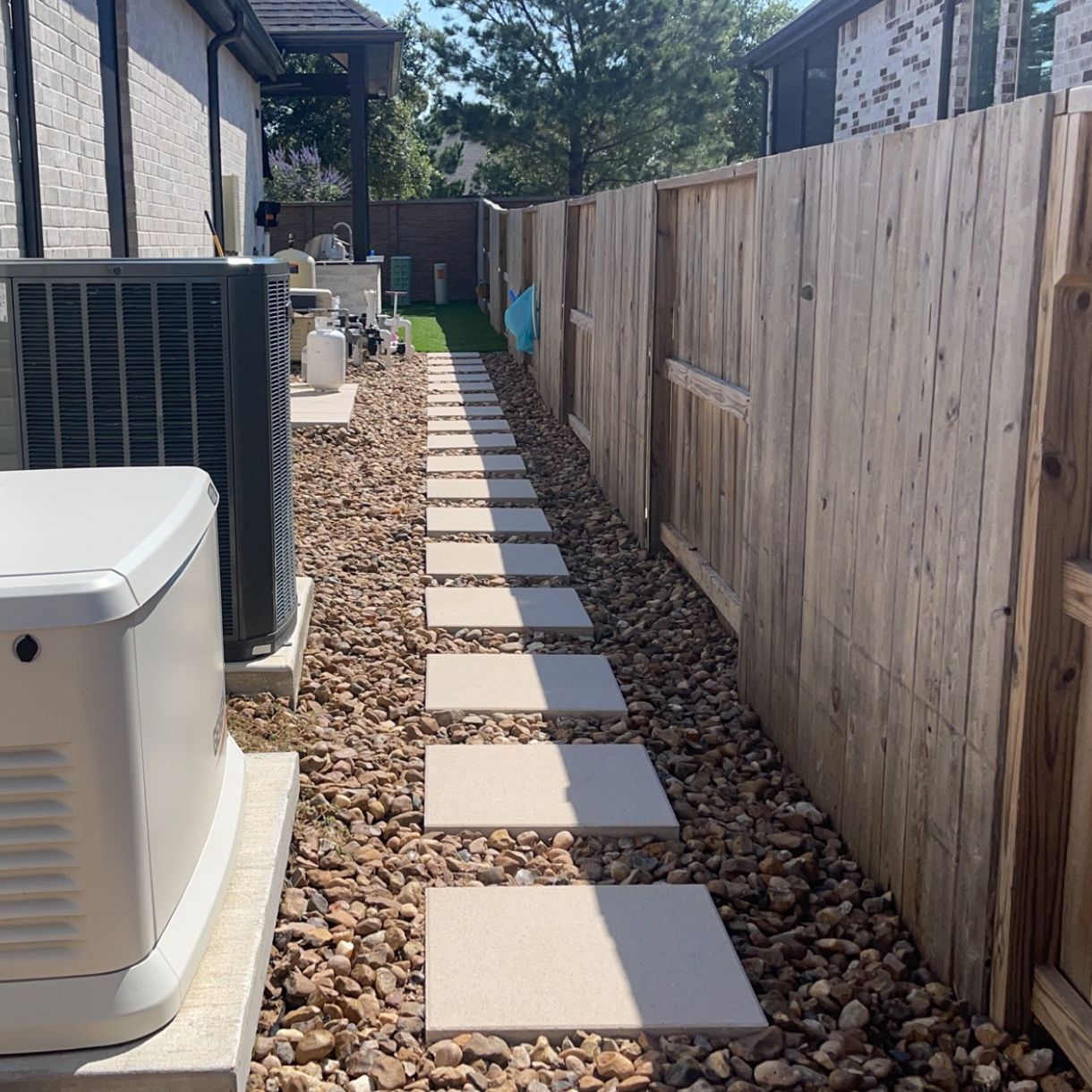 A walkway leading to a house with a wooden fence