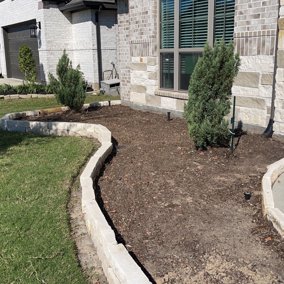 A brick house with a lush green lawn in front of it.