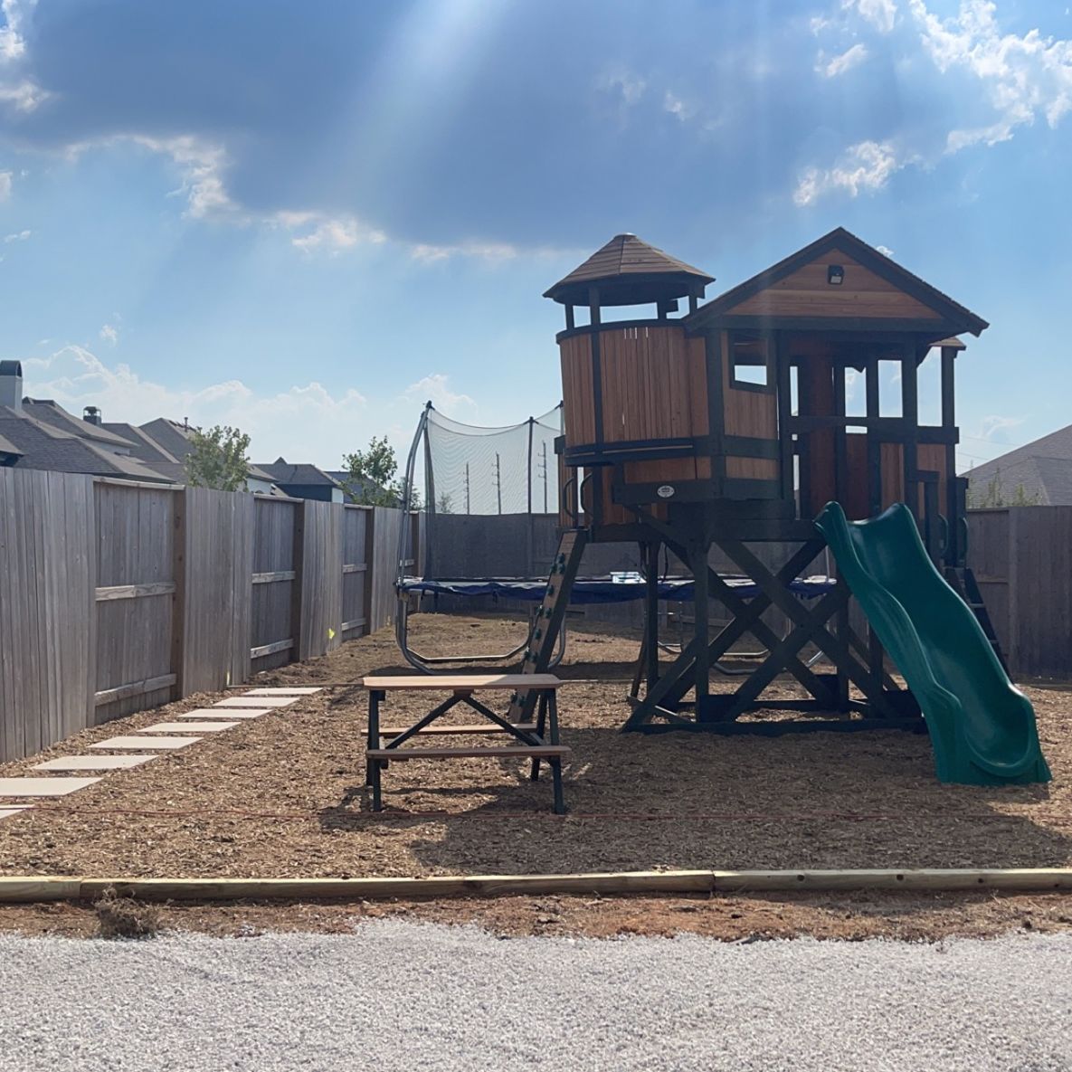 A wooden playhouse with a slide and a picnic table