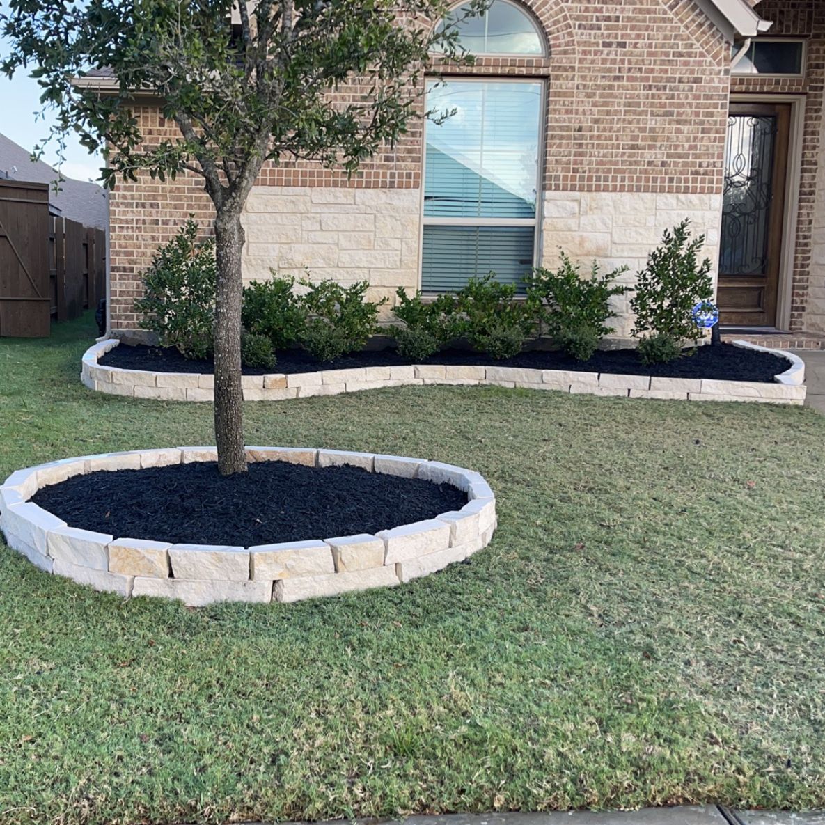 A brick house with a tree in the middle of the yard