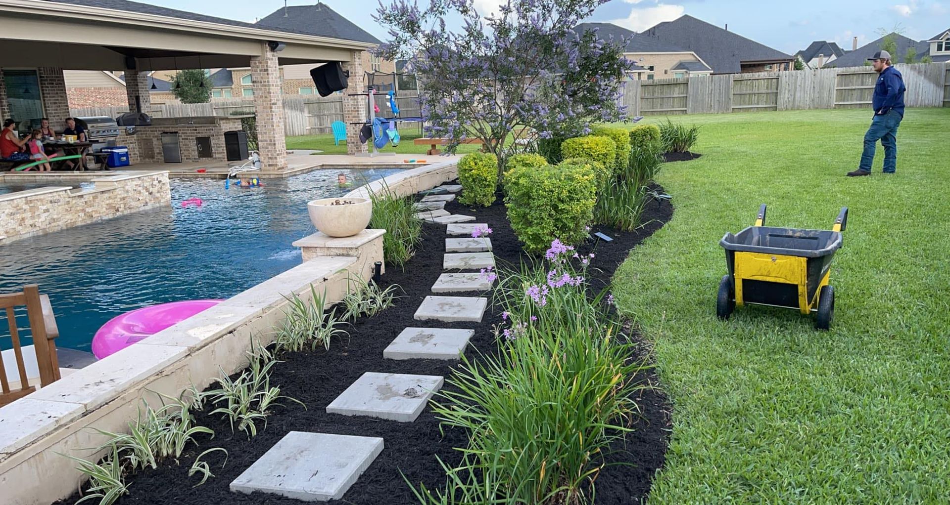 A man is standing in a backyard next to a pool.