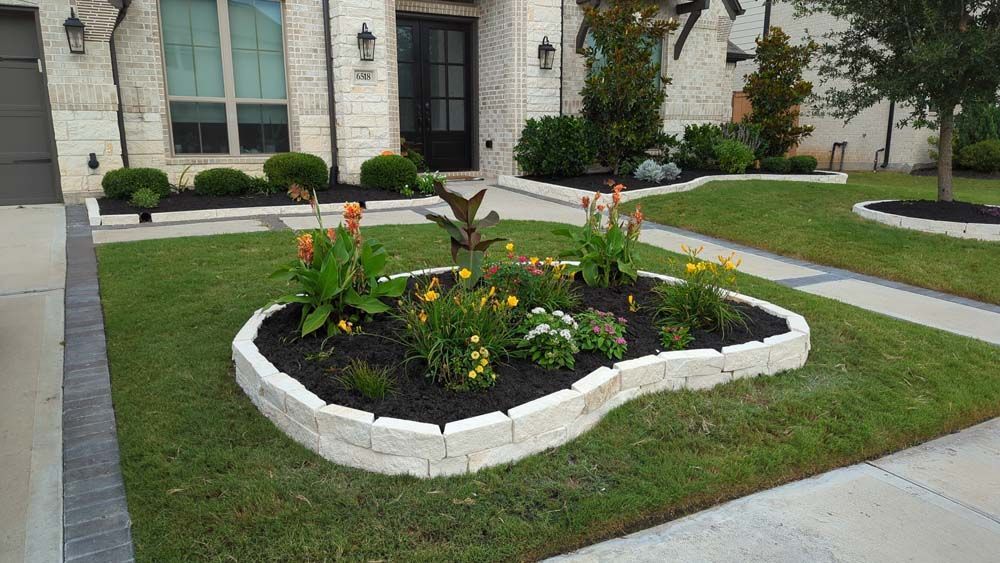 A lawn with a flower bed in the shape of a heart in front of a house.