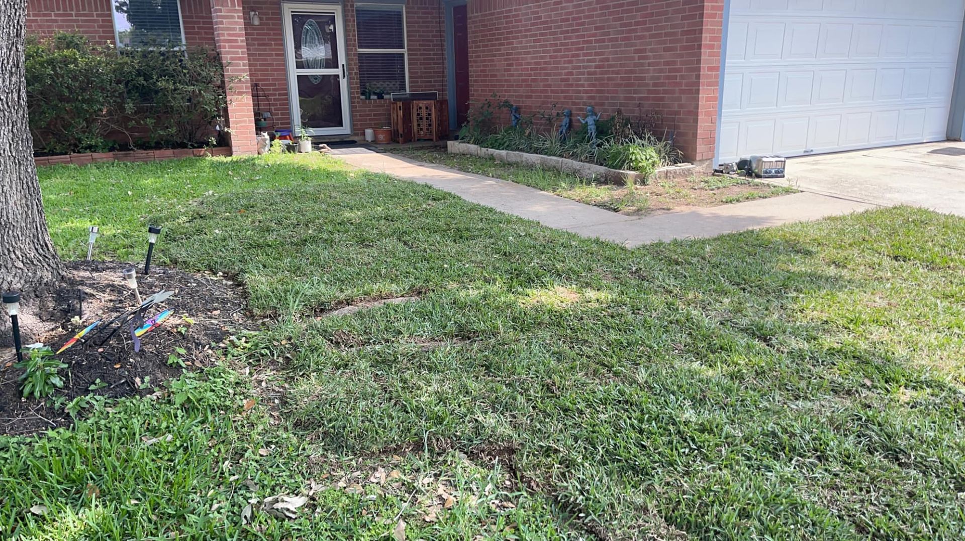 A lush green lawn is in front of a brick house.