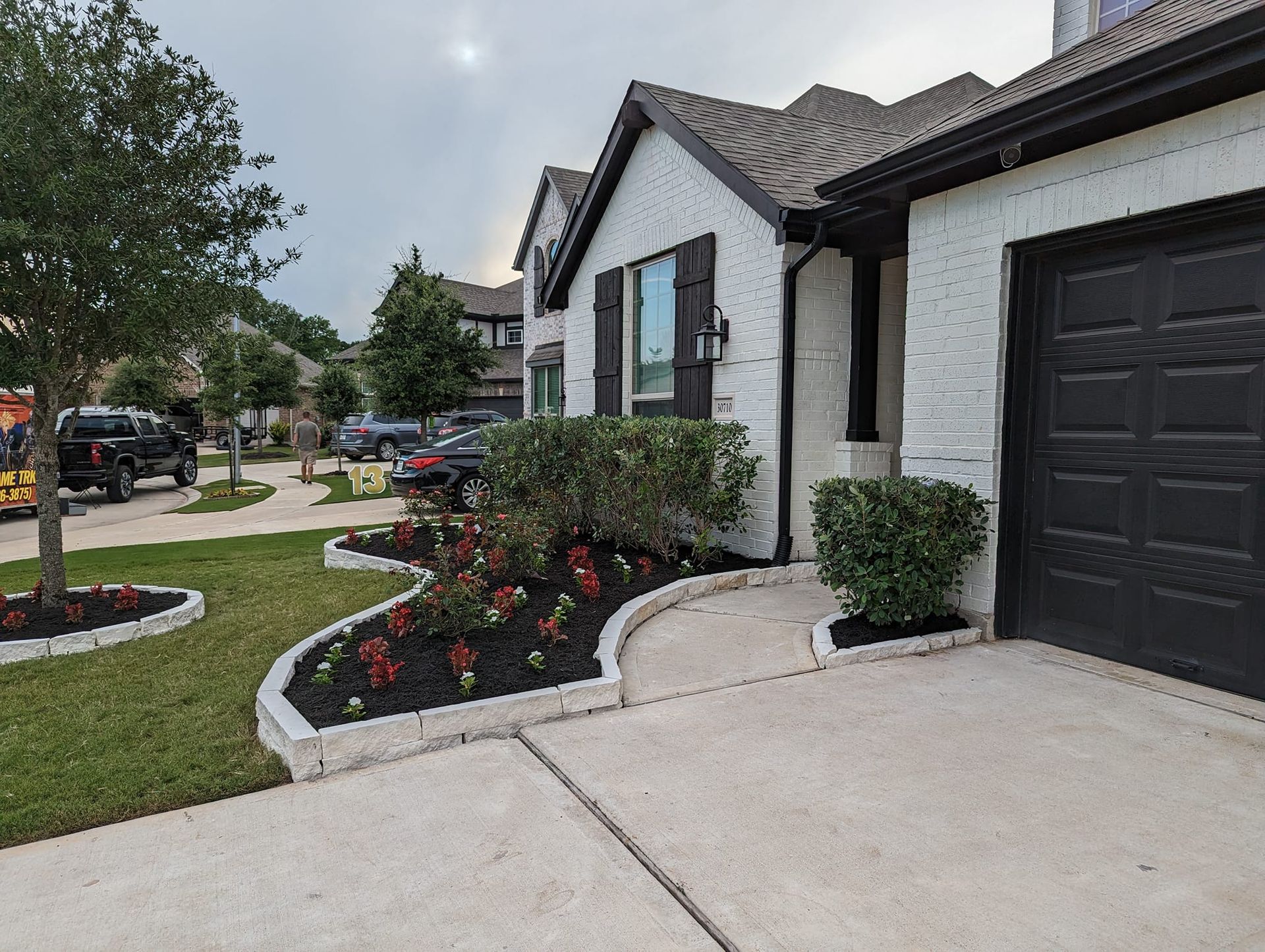 A white house with a black garage door and a walkway leading to it.