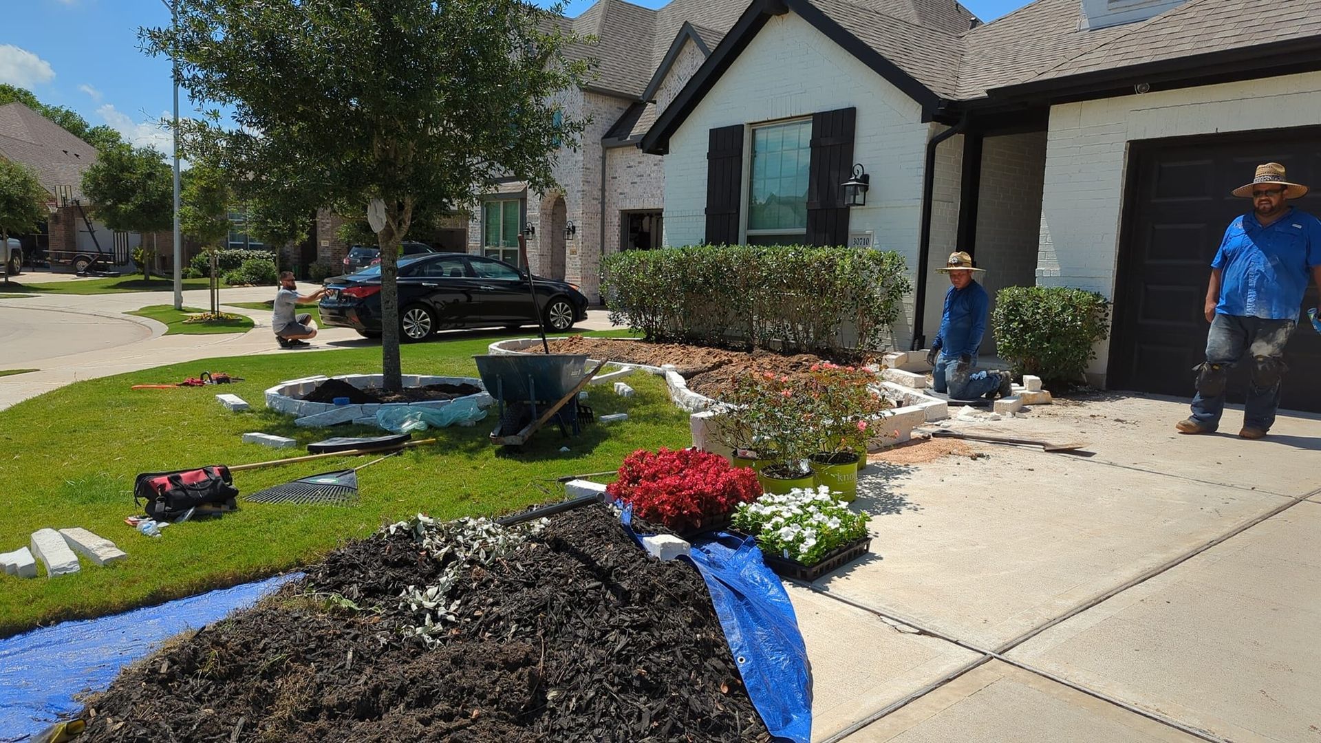 Two men are working on a lawn in front of a house.