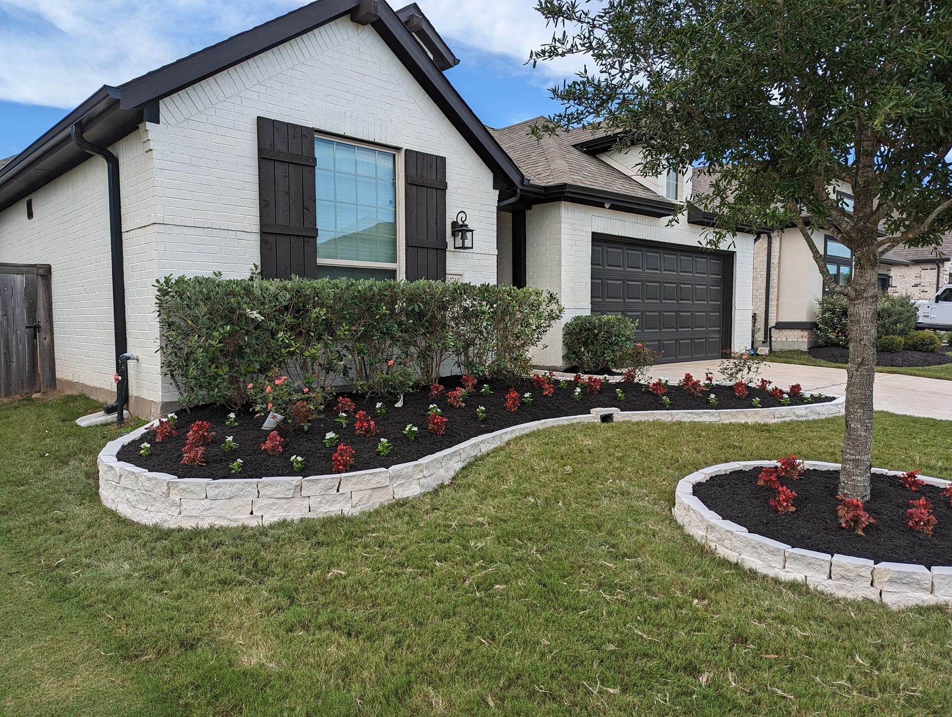 A white house with a lush green lawn and a tree in front of it.