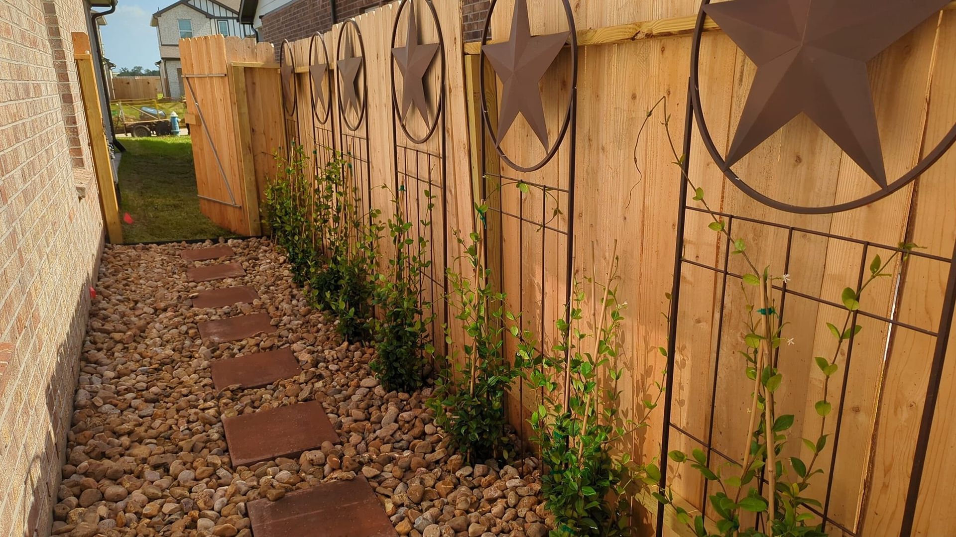 A wooden fence with a star on it is surrounded by rocks and plants.