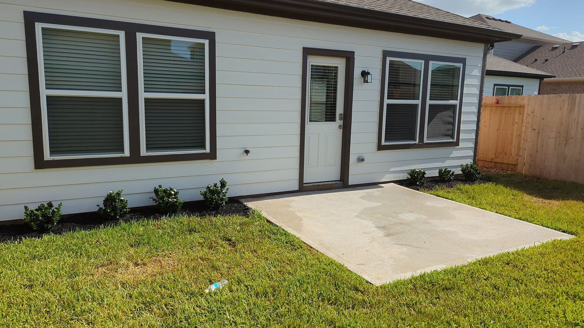 A white house with brown trim is sitting on top of a lush green lawn.