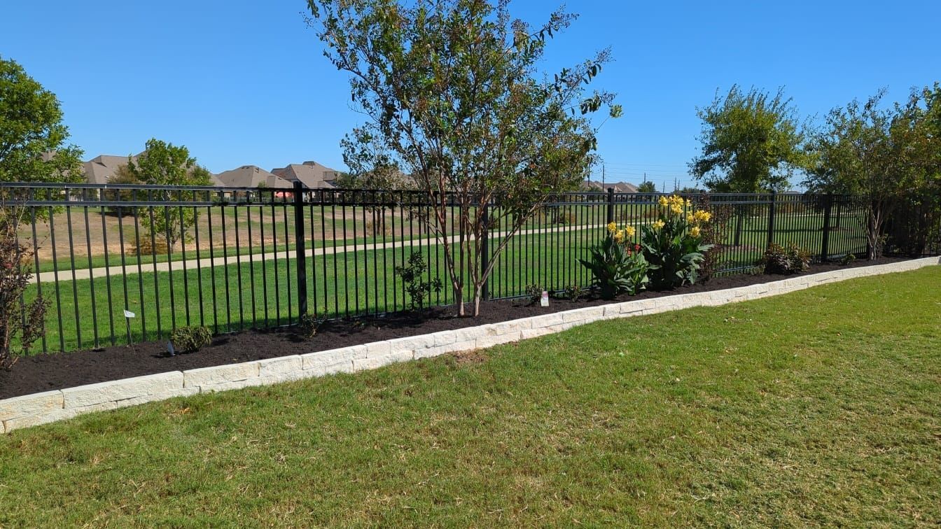 A black metal fence surrounds a lush green lawn.