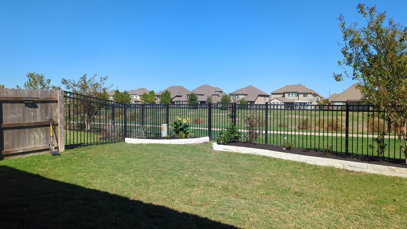 A backyard with a fence surrounding it and houses in the background.