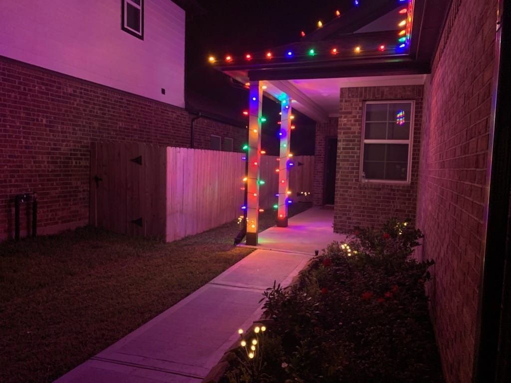 A walkway leading to a house decorated with christmas lights at night.