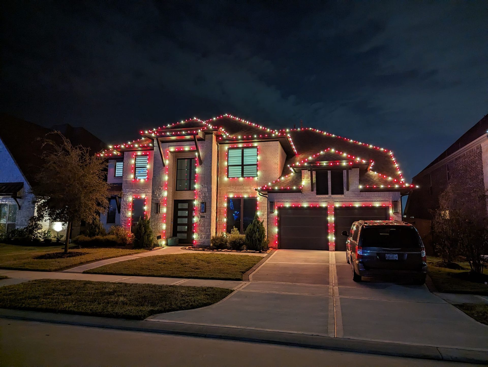 A large house is decorated with christmas lights at night.