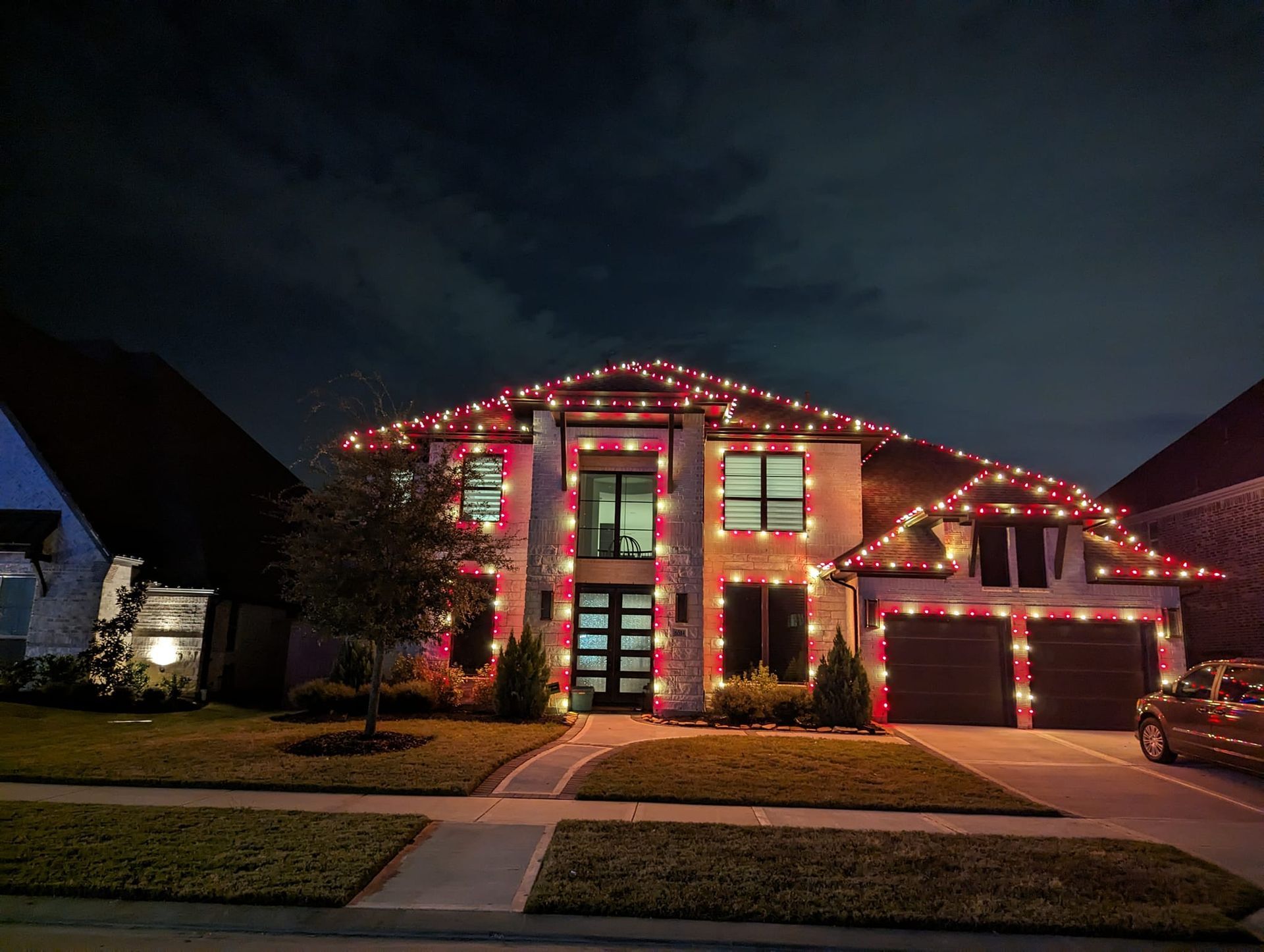 A large house is decorated with christmas lights at night.