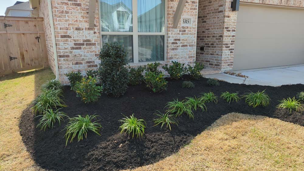 A brick house with a black mulch bed in front of it.