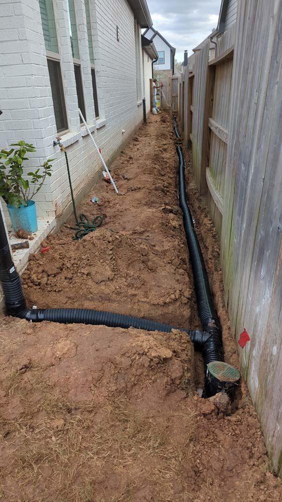 A drainage system is being installed in the backyard of a house.