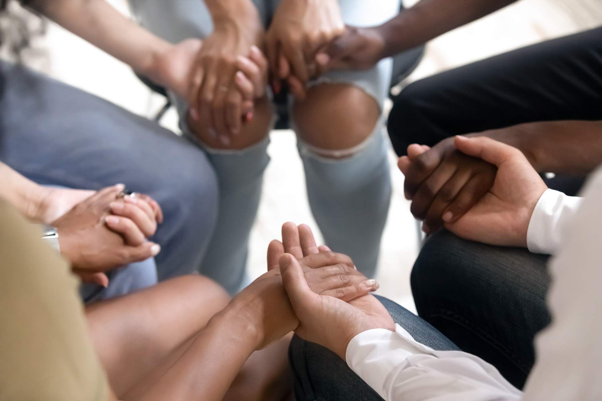 a group of people are sitting in a circle holding hands .