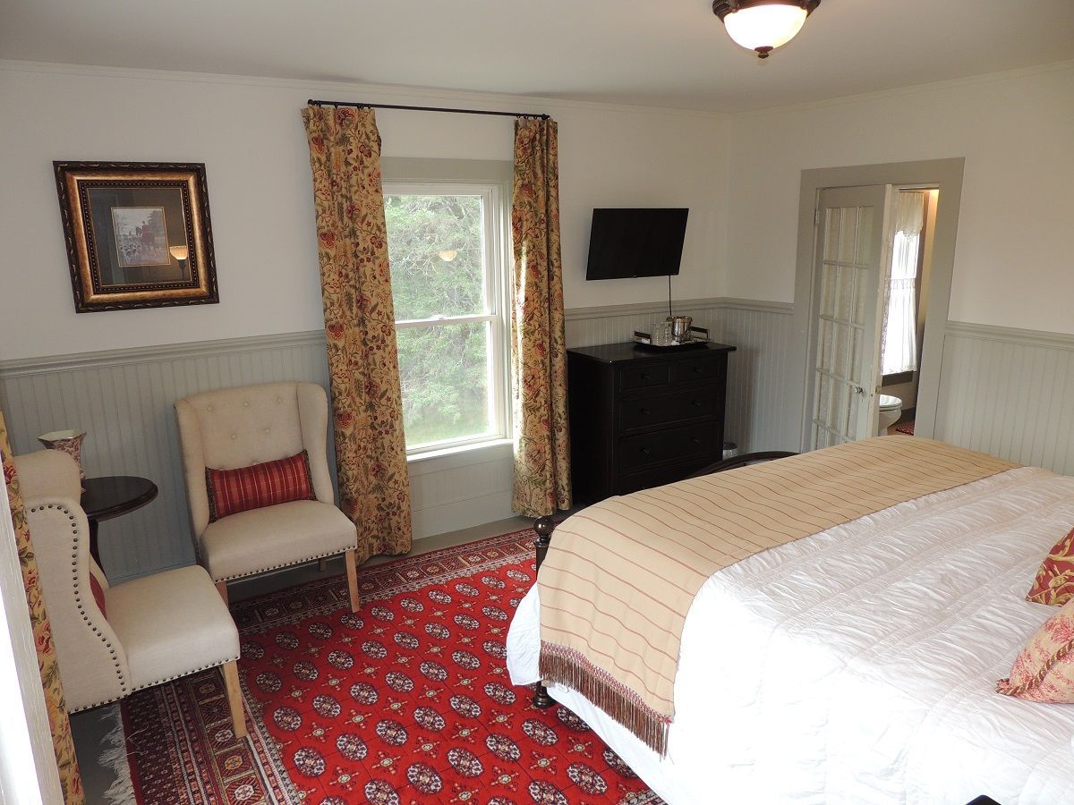 A bedroom with a king size bed a chair and a television