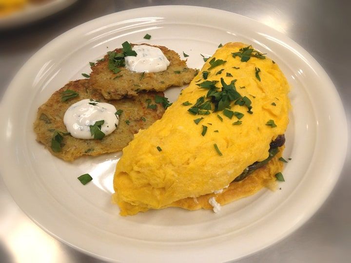 A white plate topped with an omelet and potato pancakes