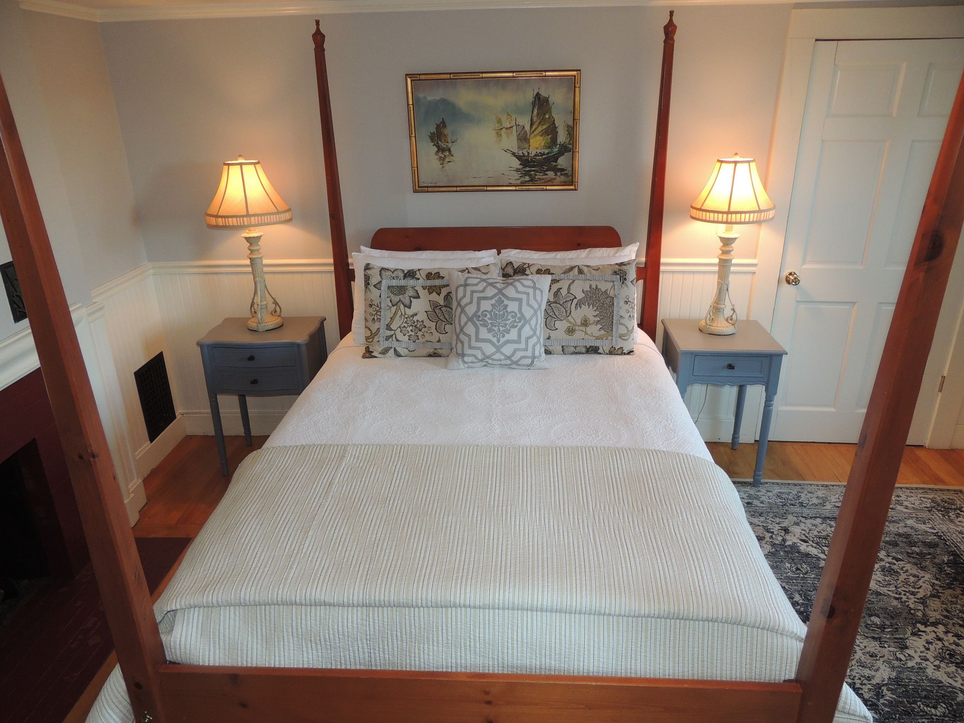 A bedroom with a four poster bed and two lamps