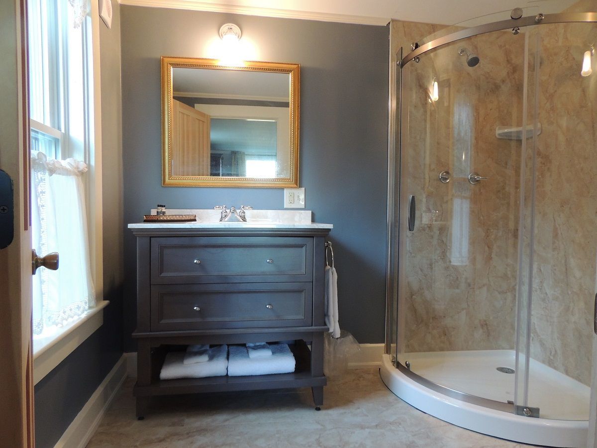 A bathroom with a sink , mirror , and shower.