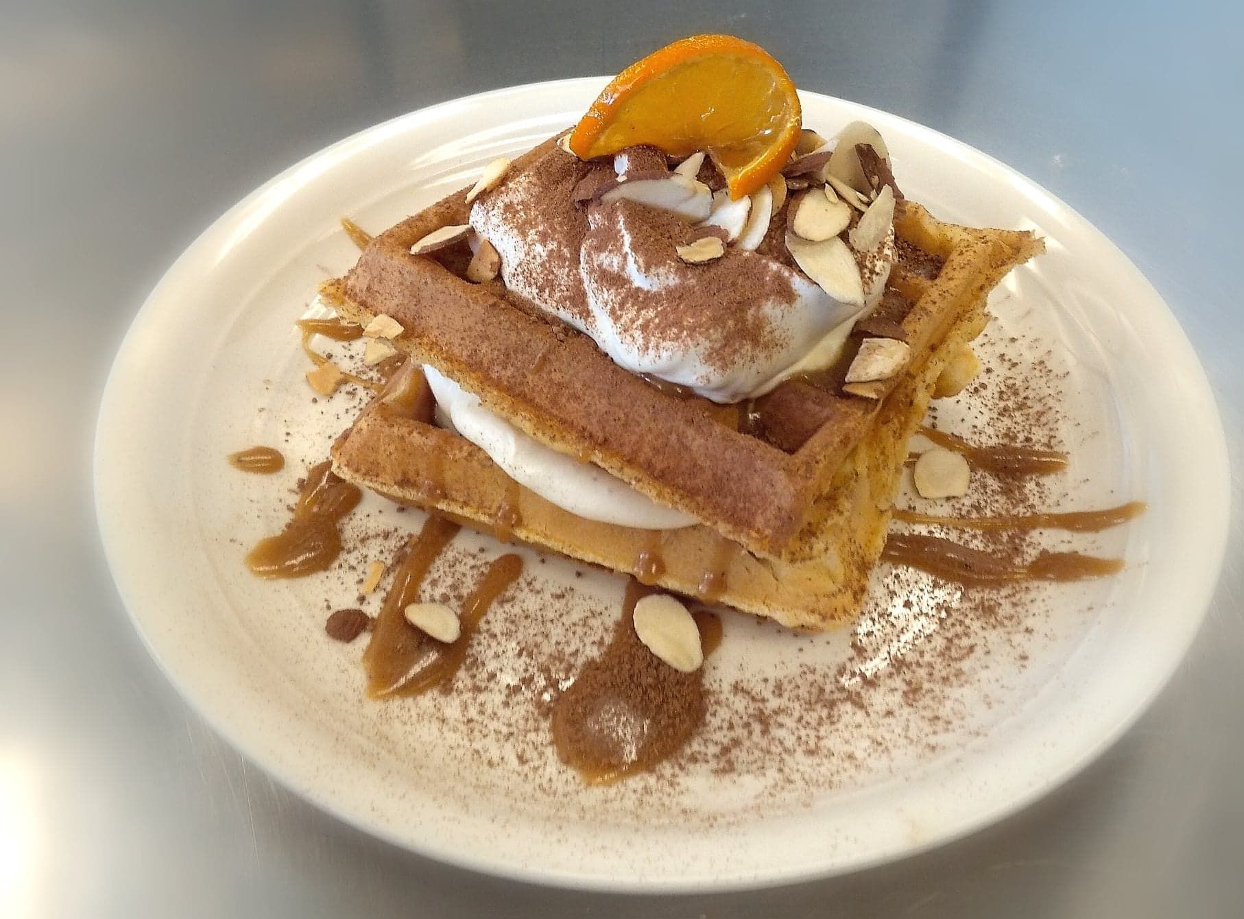 A white plate topped with a waffle and whipped cream