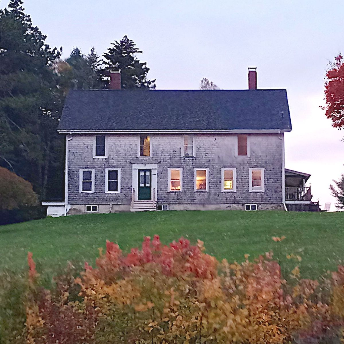 A large house is sitting on top of a lush green hill.