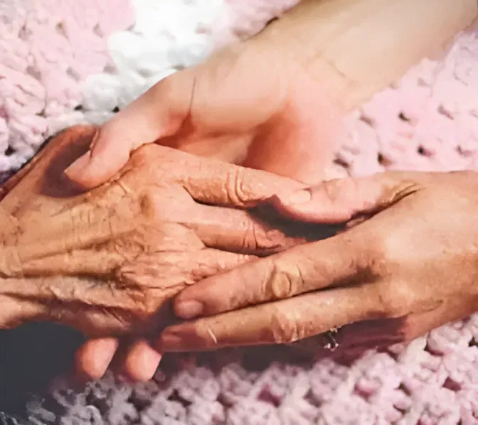 Hands of older and younger person, clasped together, possibly offering comfort.