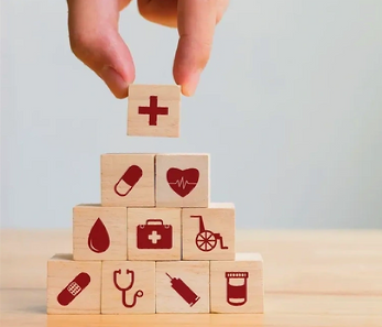 Hand placing a health symbol block on a pyramid of medical icon blocks.