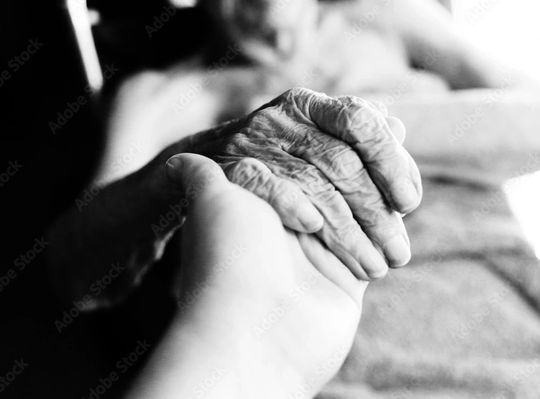 A hand holding an elderly person's wrinkled hand, black and white.