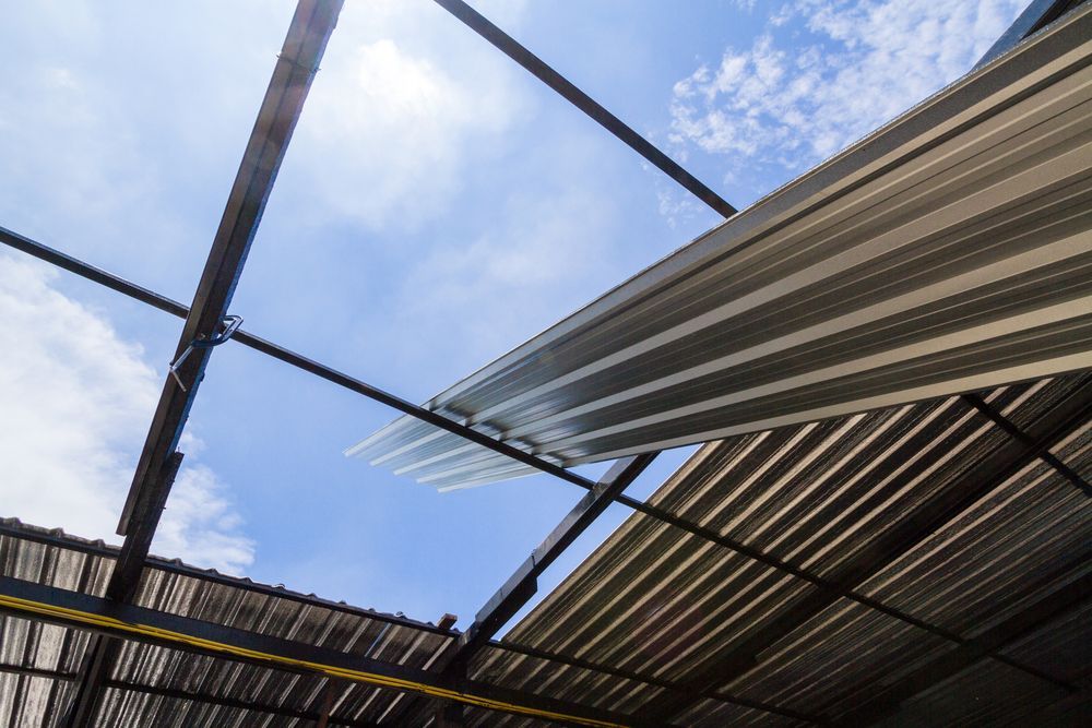 View of a Damaged Roof With Corrugated Metal Panels. Blue Sky is Visible — Coffs Coast Roofing In Nambucca, NSW
