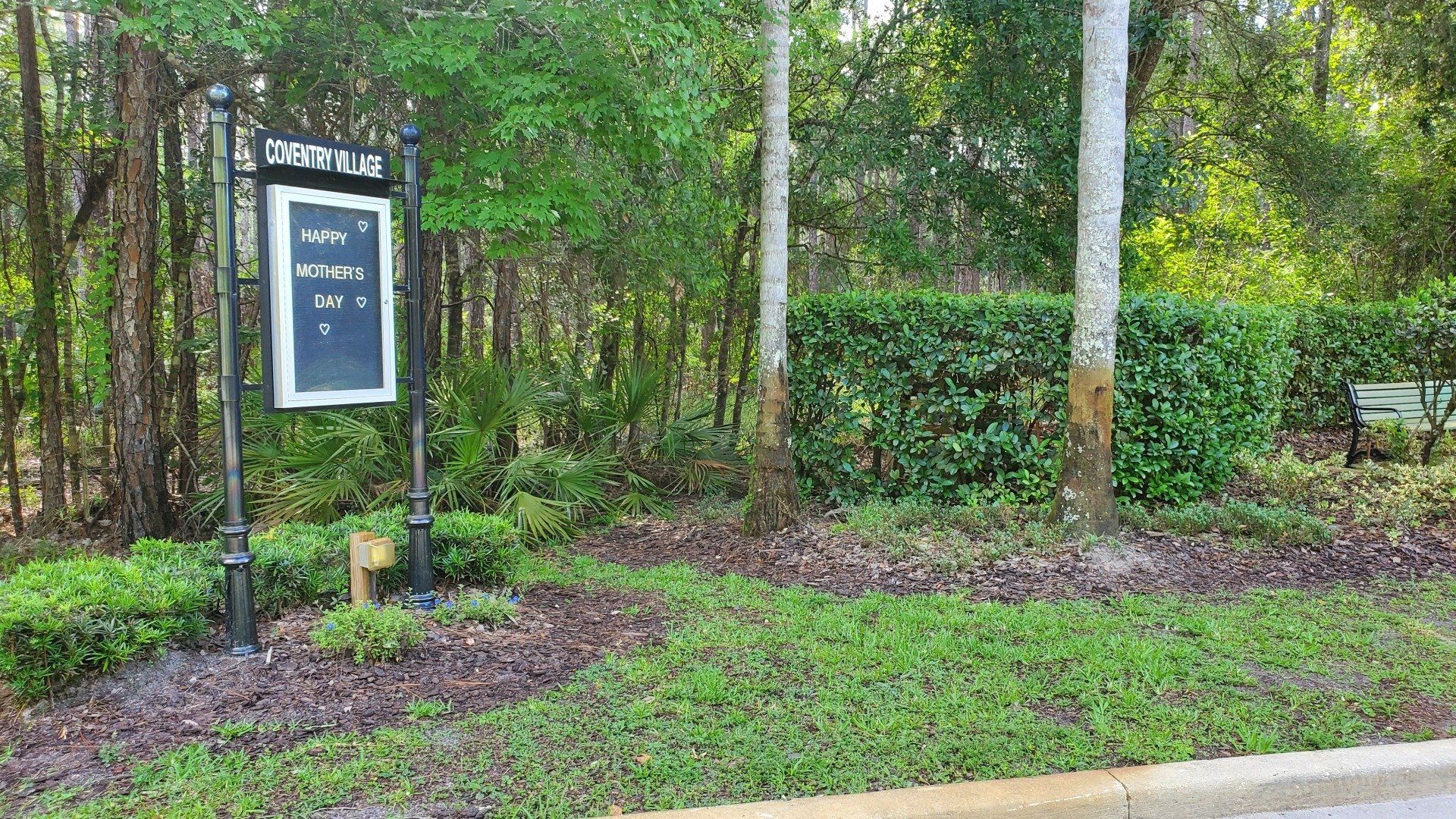 A sign is sitting in the middle of a lush green forest.