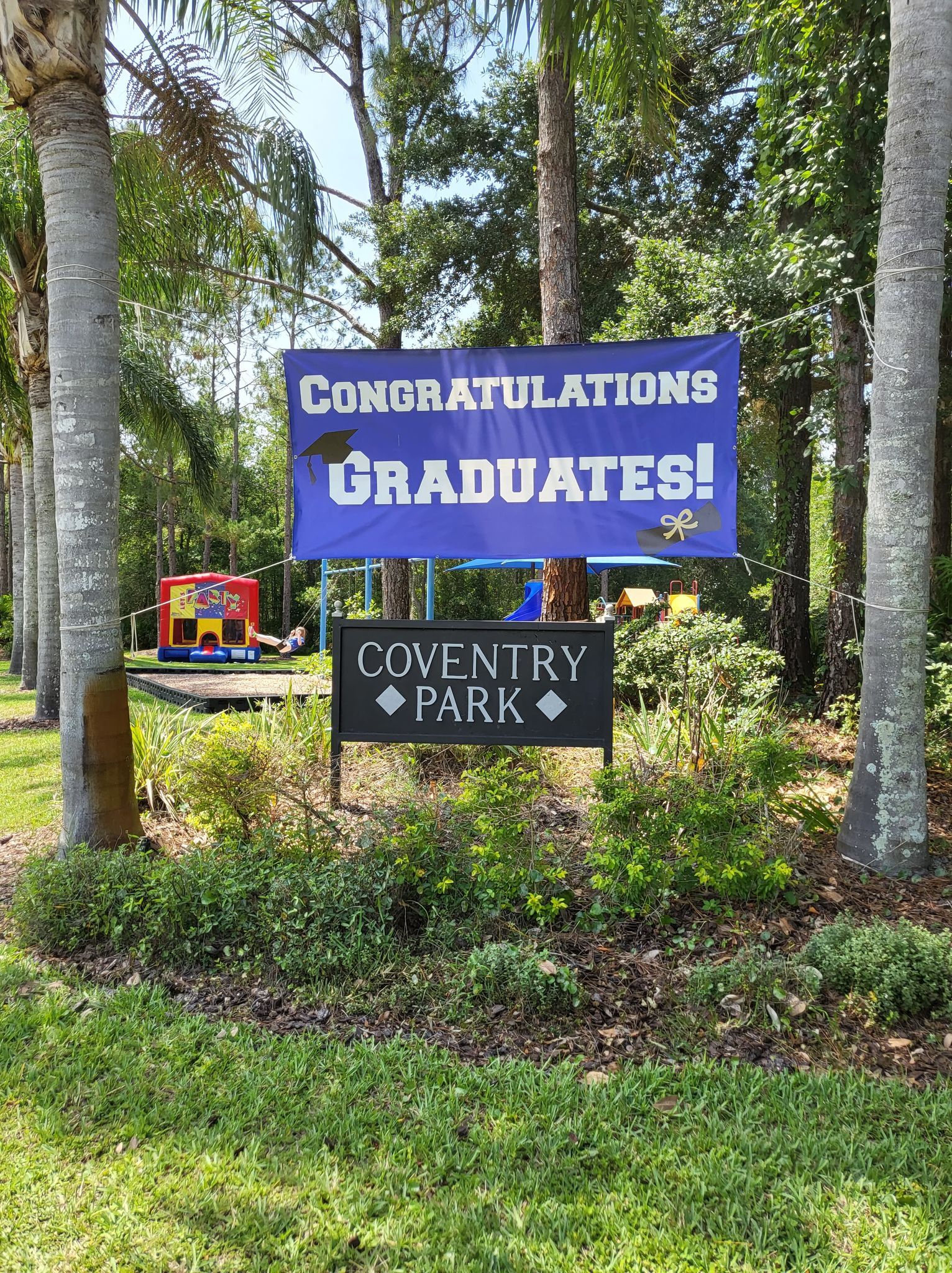 A sign that says `` congratulations graduates '' is in the middle of a park.