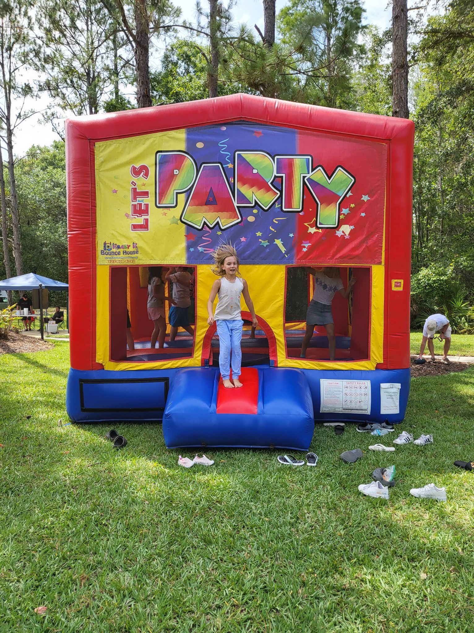 A little girl is standing in front of a bouncy house.
