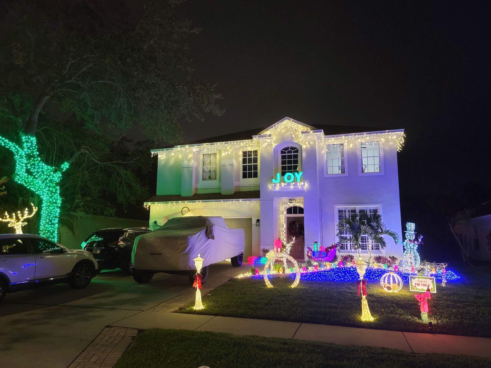 A house is decorated with christmas lights and decorations at night.
