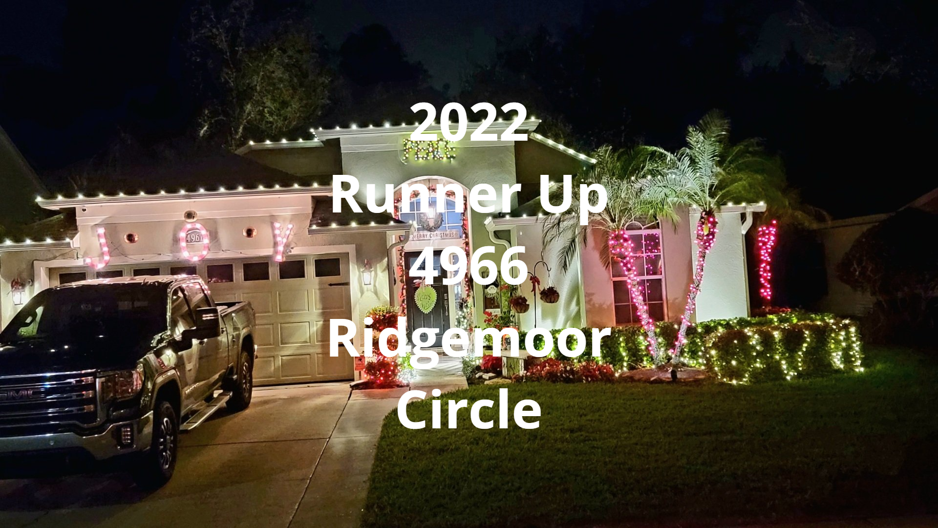 A car is parked in front of a house decorated for christmas.