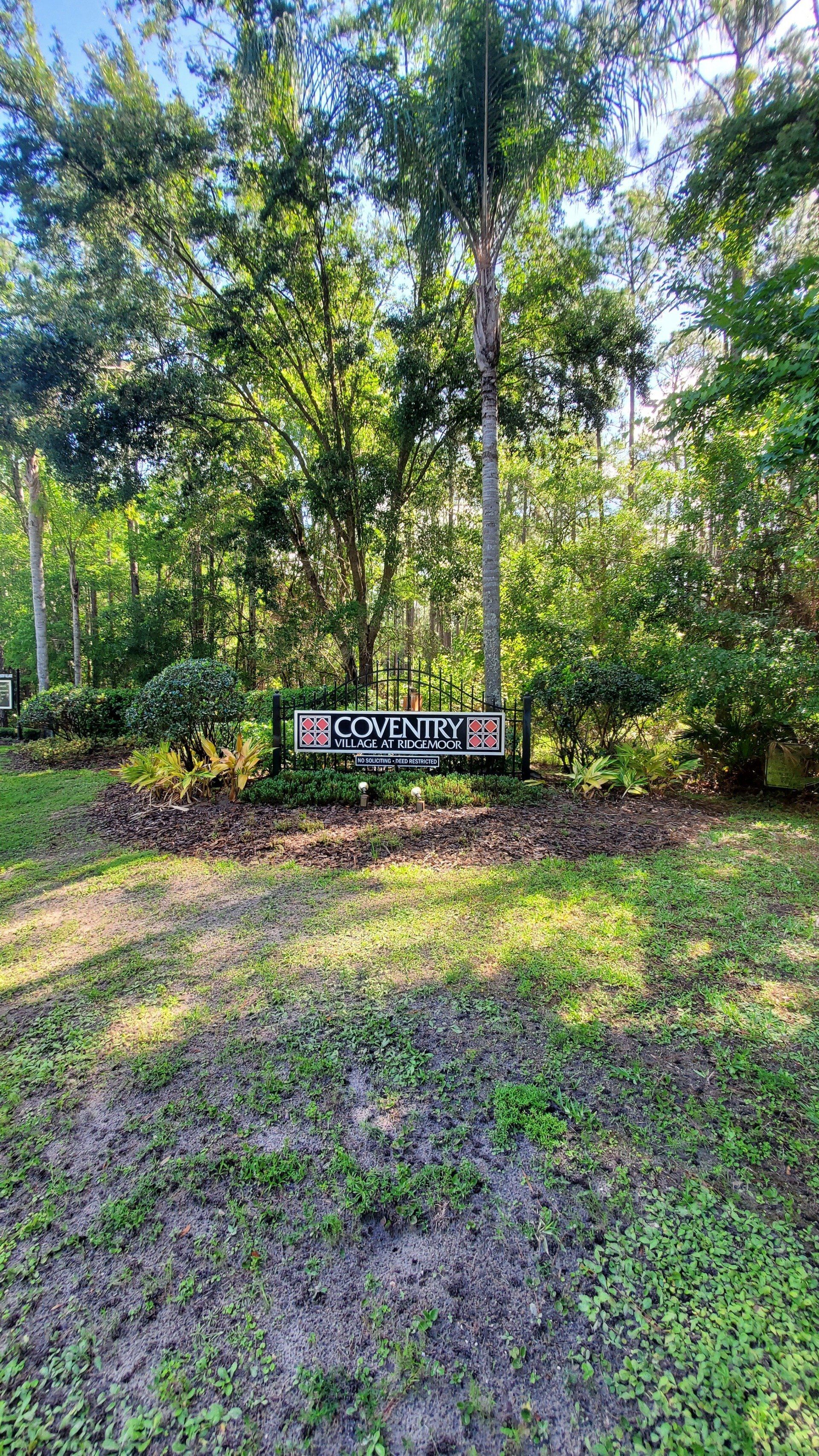 A sign in the middle of a lush green field surrounded by trees.