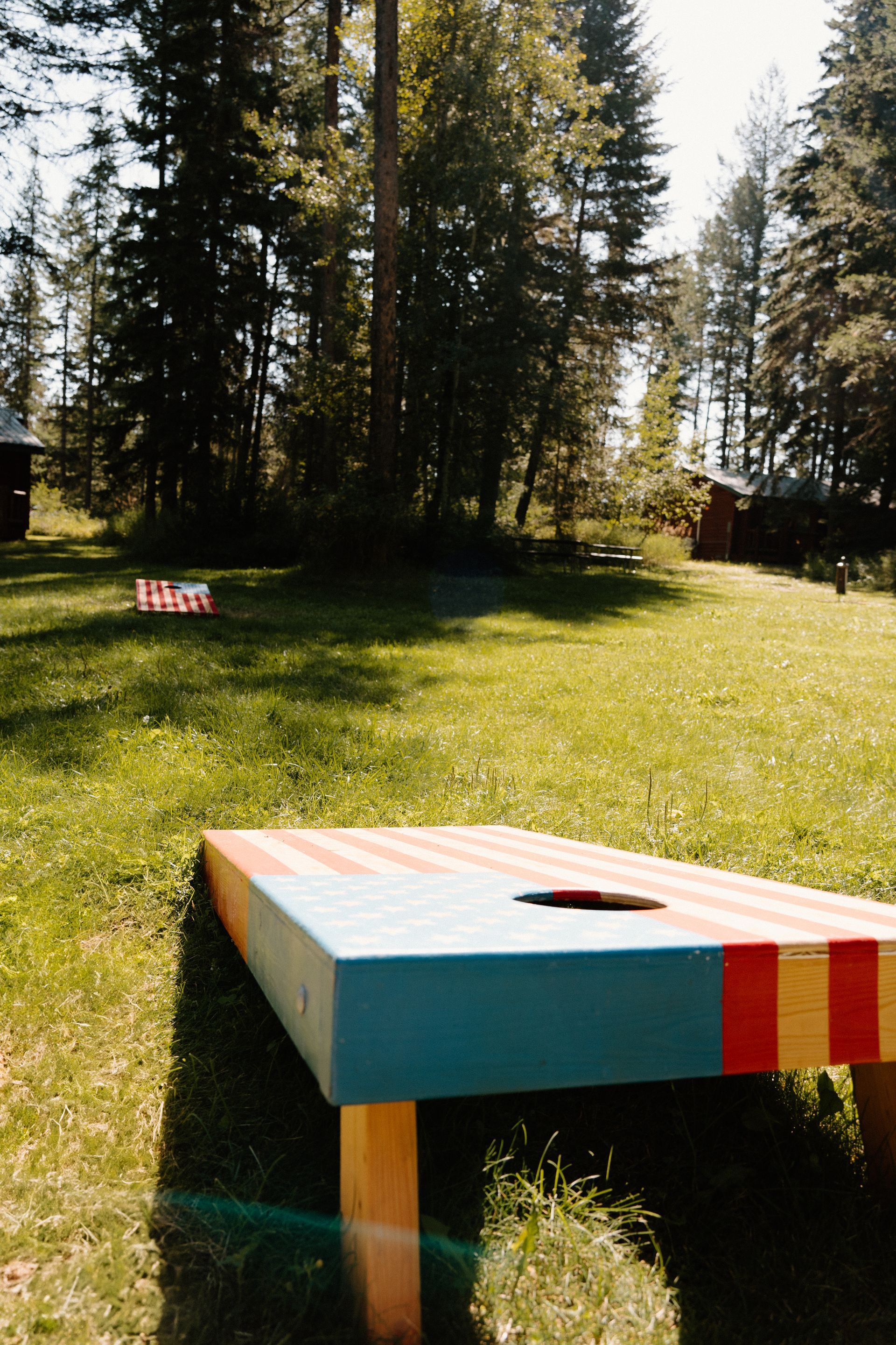 A colorful cornhole board is in the middle of a grassy field