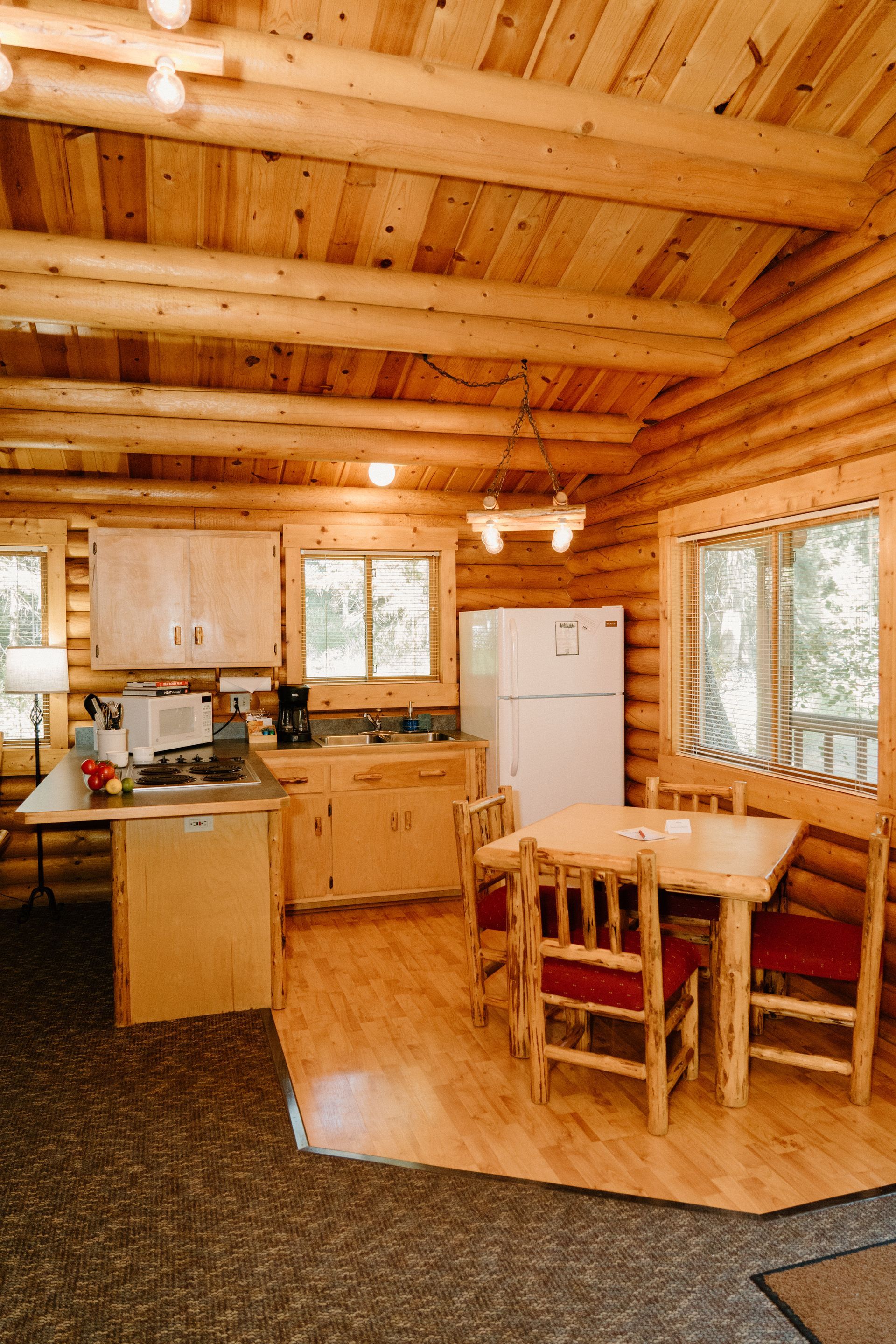 A log cabin with a kitchen , dining table and chairs.