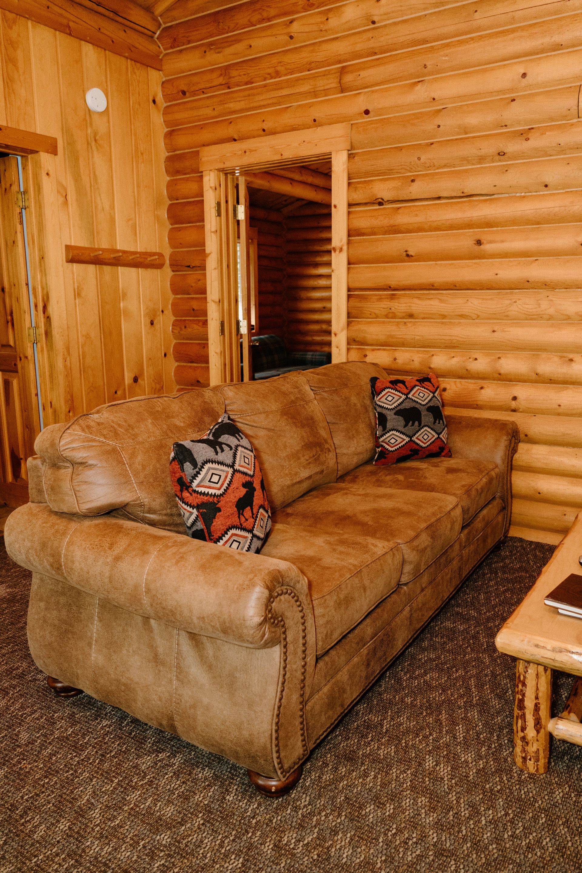 A living room in a log cabin with a couch and a coffee table.