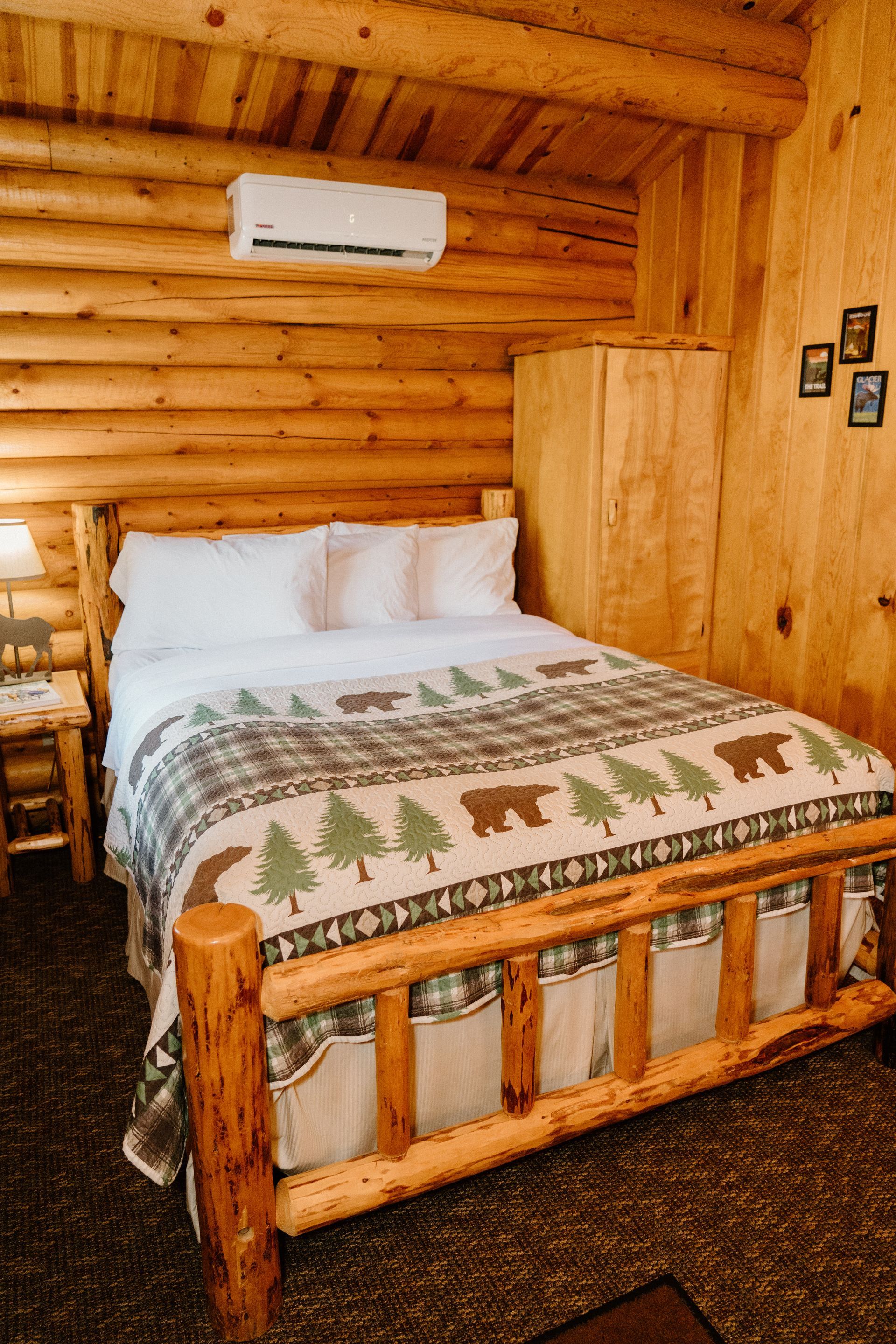 A bed in a log cabin with a bear blanket on it.