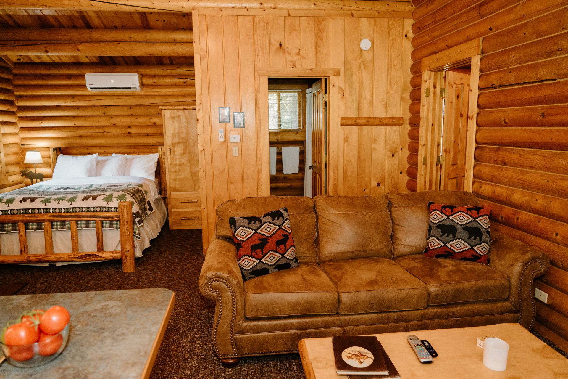 A living room in a log cabin with a couch and a bed.