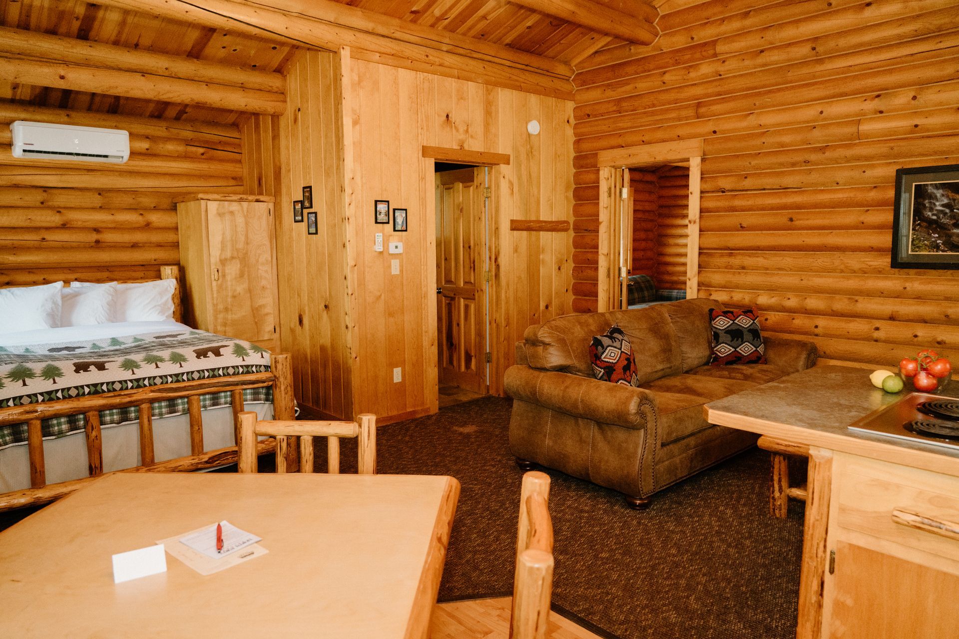 A log cabin with a bed , couch , table and chairs.