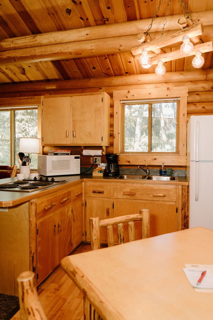 A kitchen in a log cabin with a table and chairs