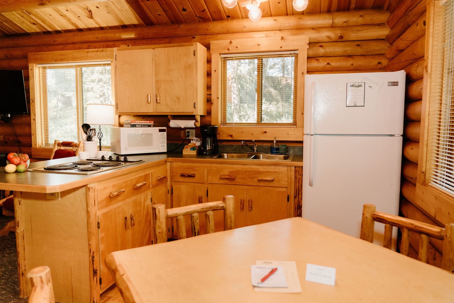 A kitchen in a log cabin with a table and chairs and a refrigerator.