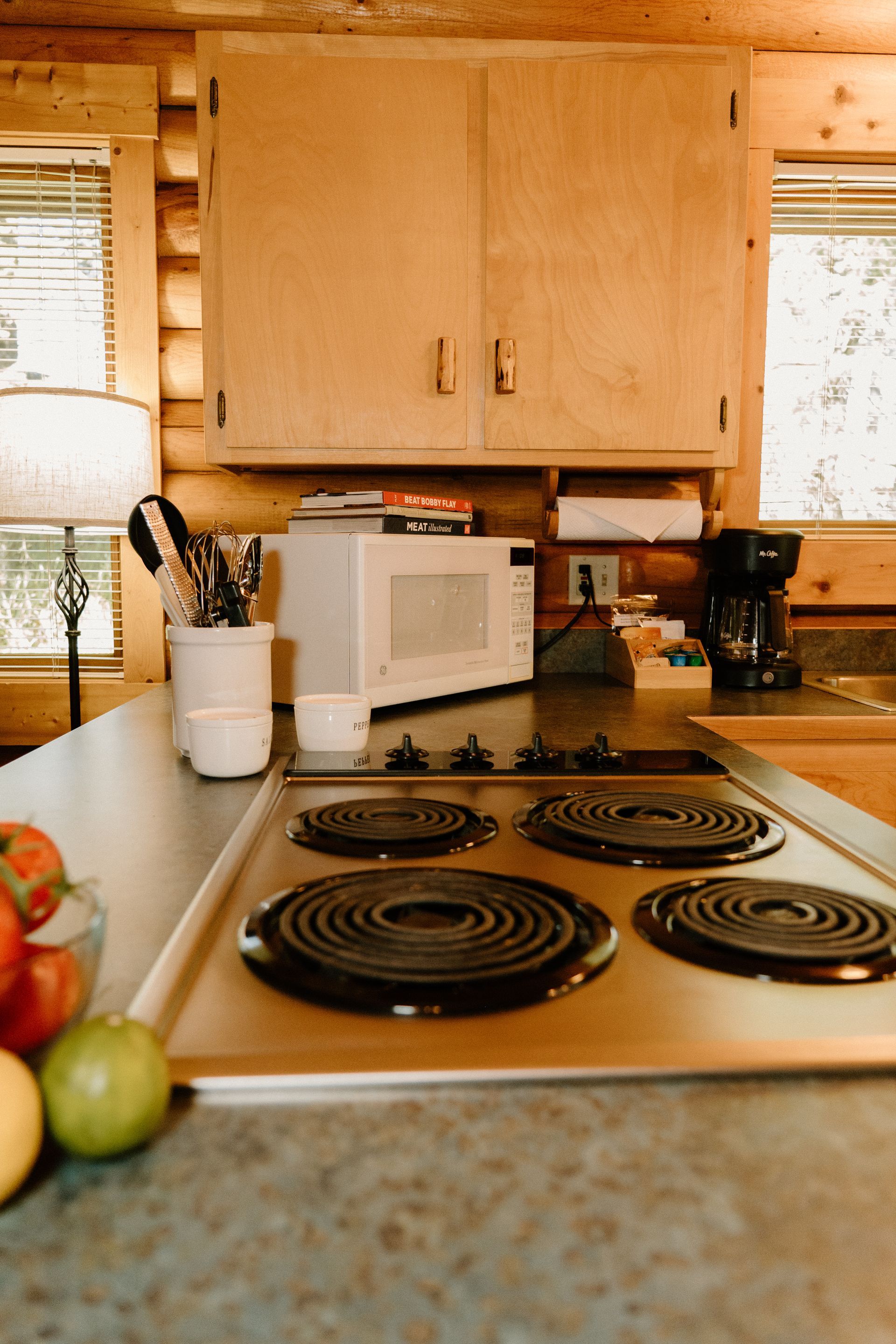 A kitchen with a stove , microwave , and fruit on the counter.