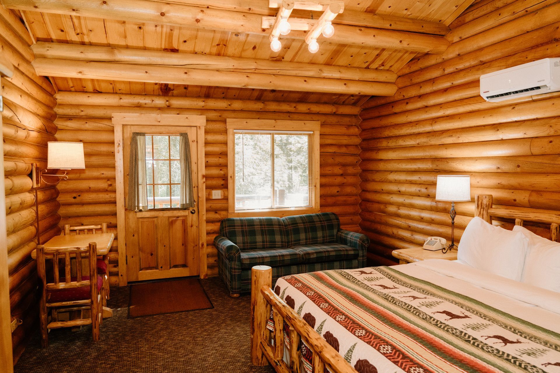 A log cabin with a bed , couch , desk and chairs.