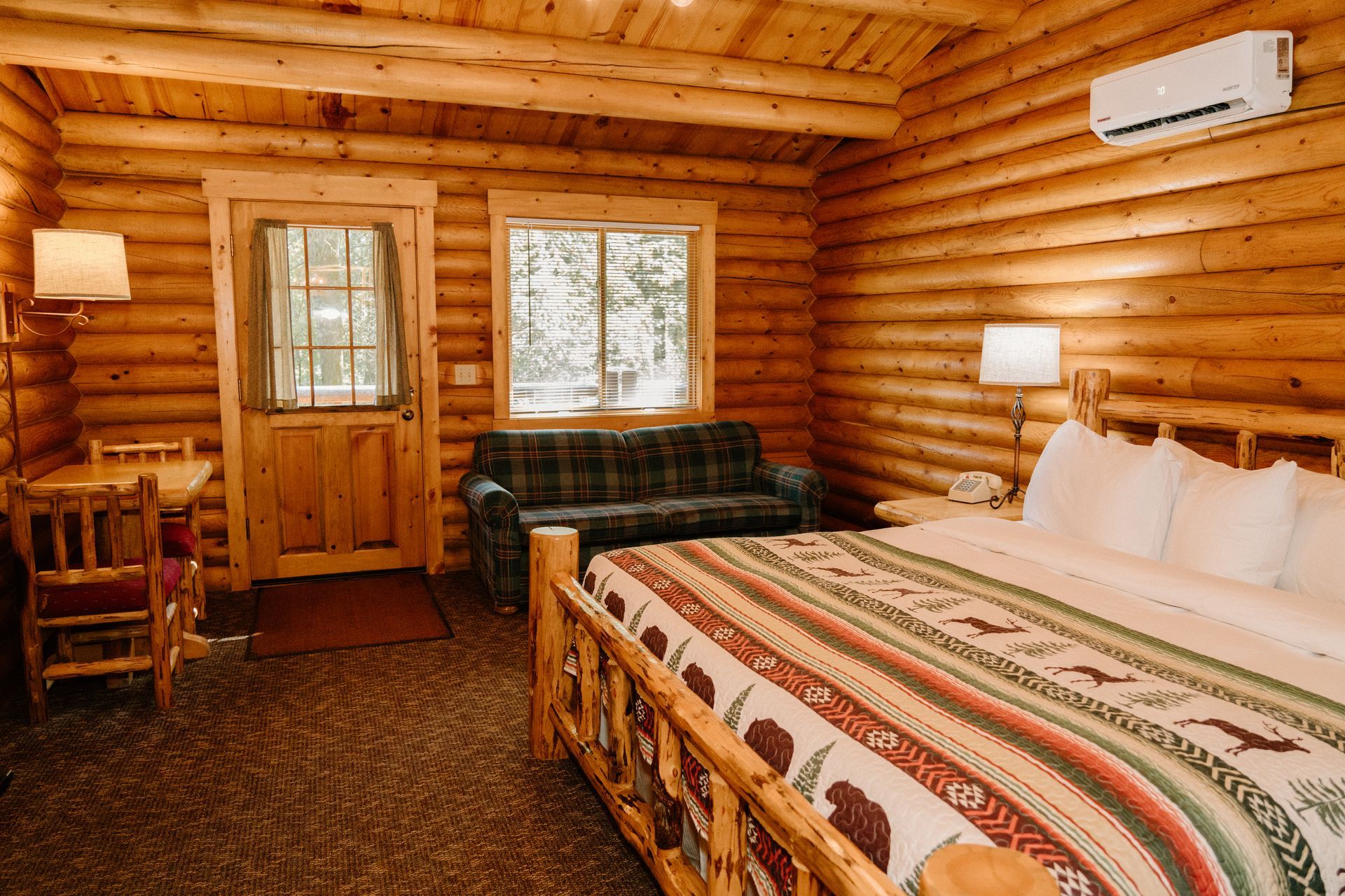 A log cabin with a bed , couch , table and chairs.