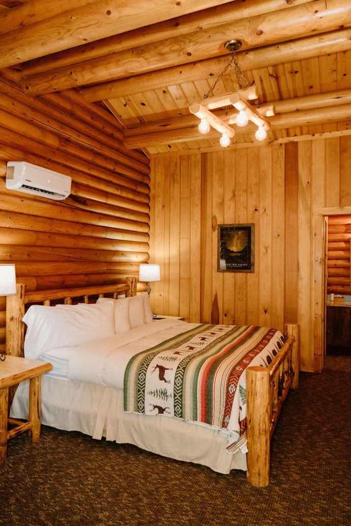 A bedroom in a log cabin with a bed and a chandelier.