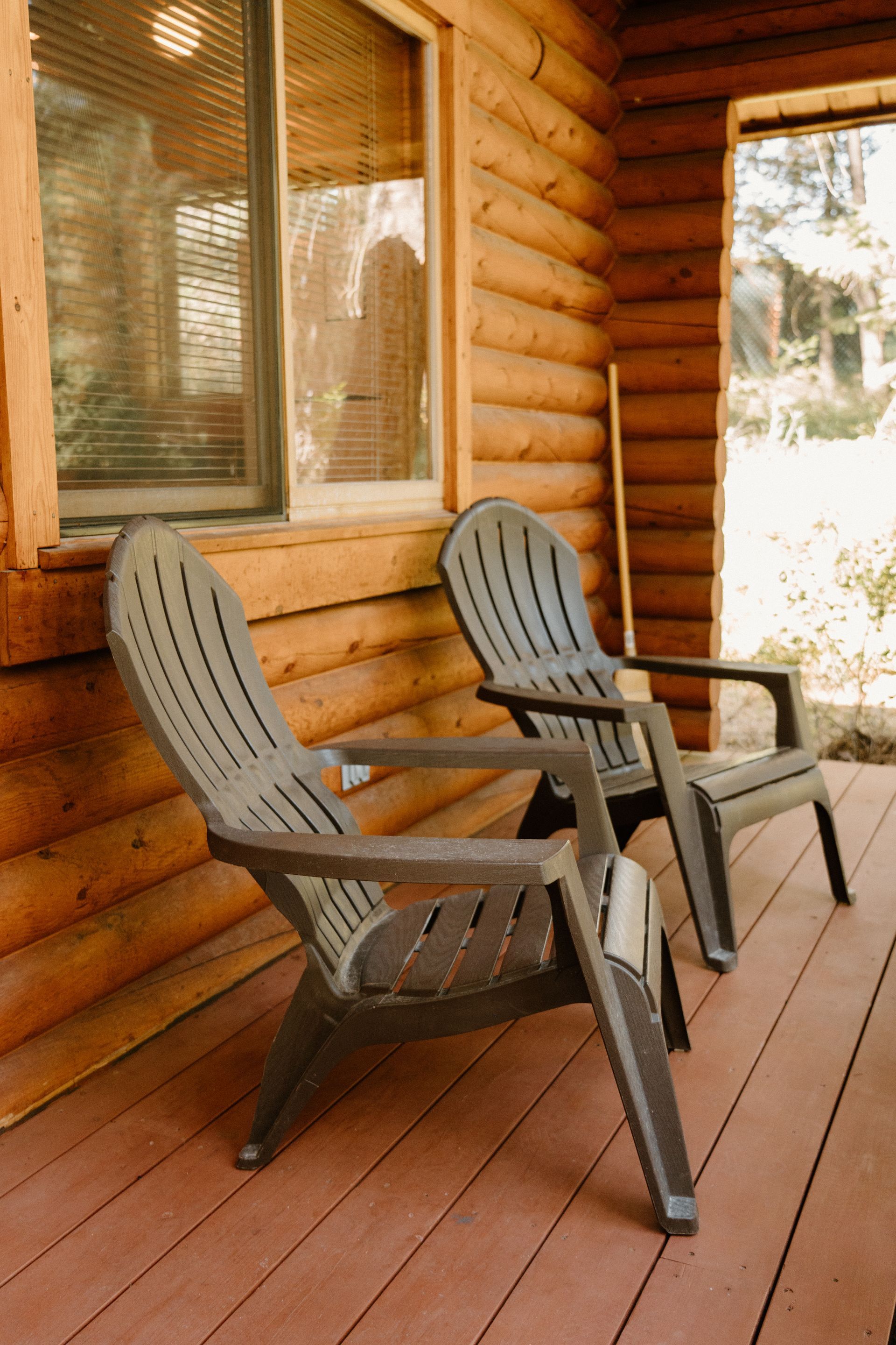 Two chairs are sitting on a porch of a log cabin.